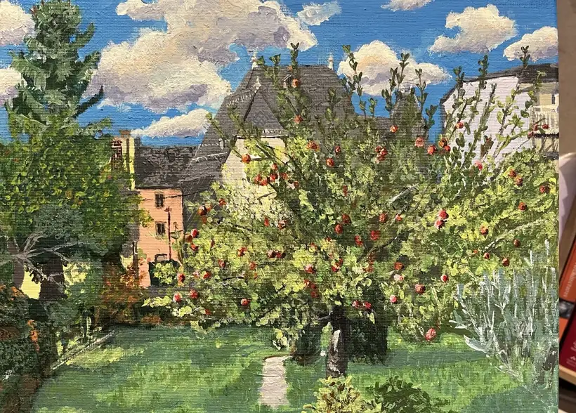Garden scene with fruit trees, bright sky and houses in the background.